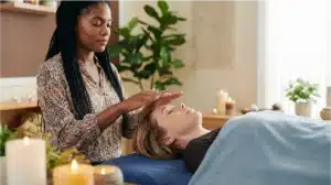 Energy healer performing Reiki healing session with client on treatment table in peaceful wellness setting Energy healer performing Reiki healing session with client on treatment table in peaceful wellness setting